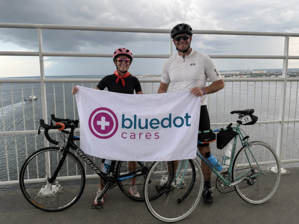 BlueDot Cares team member poses with a BlueDot Cares banner after raising more than $10,000 during the Alzheimer's Association Ride to End ALZ.